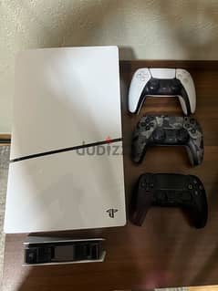 ps5 slim 1 tb with 3 original controllers and a charging stand 0